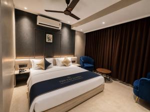 a hotel room with a large bed and blue chairs at The Bay Suites - NIS in kolkata