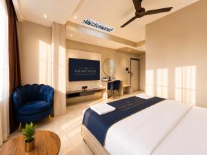 a bedroom with a large bed and a blue chair at The Bay Suites - NIS in kolkata