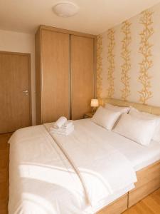 a large white bed with two towels on top of it at Urban Temple Apartment near Cathedral Free Parking in Podgorica