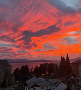 a sunset over the water and a city at Bariloche Apartment in San Carlos de Bariloche