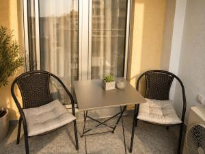 a table and two chairs sitting next to a window at Urban Temple Apartment near Cathedral Free Parking in Podgorica +5 photos