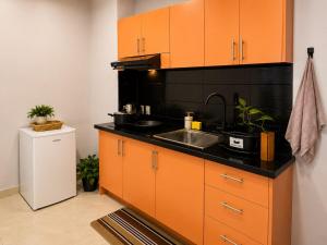 a kitchen with orange and black cabinets and a sink at DOLFIJN STUDIOS Comfortable 1BR Apartment Fast WiFi AC North Paramaribo in Paramaribo