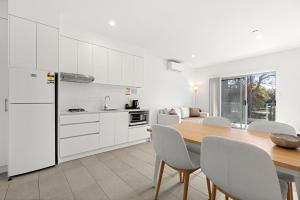 a kitchen with a wooden table and white cabinets at Modern 1 Bed Apartment - 6 Min Walk to Beach in Callala Beach