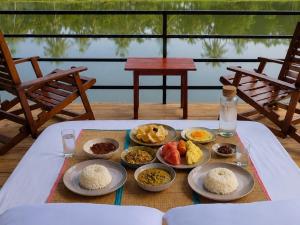 a table with plates of food on a table with chairs at Lake Cabana in Udawalawe +65 photos