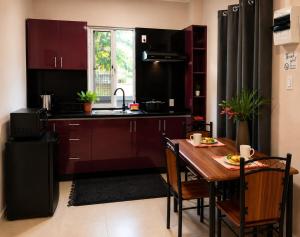 a kitchen with red cabinets and a wooden table at DOLFIJN STUDIOS Stylish 2BR Apartment Fast WiFi AC Near Center in Paramaribo