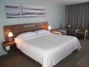a hotel room with a large white bed and two chairs at Auberge De La Baie in Caraquet
