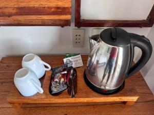 a tea kettle and a cup on a wooden counter at Toba Crest Vue in Parapat