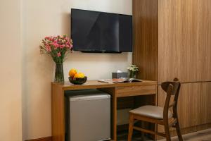 a desk with a television and a vase of flowers at The Sono Hanoi Hotel in Hanoi