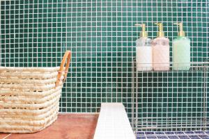 a green tiled wall with two bottles on a shelf at Roku Hostel Hiroshima in Hiroshima