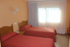 um quarto de hotel com duas camas e uma janela em Hostal Sandino em Villodrigo