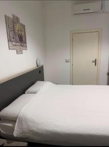 a bedroom with a white bed and a door at La voglia albergo in Villanova sullʼArda