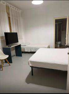 a room with two beds and a desk with a television at La voglia albergo in Villanova sullʼArda