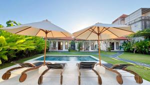 two chairs and two umbrellas next to a swimming pool at ANANDA Bingin Guesthouse in Bingin Beach