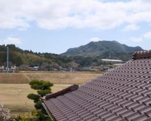a roof of a house with a mountain in the background at Omoya Kitahata in Karatsu