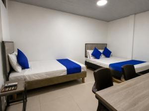 a room with two beds and a table and a desk at HOTEL ELITE in Cali