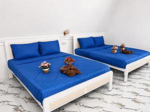 two beds in a room with blue sheets and flowers at Blue Zone Hostel in Kaôh Rŭng (3) +16 photos