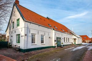 a large white building with an orange roof at Ferienwohnung Auster in Manslagt