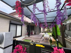 a patio with purple flowers hanging from a building at GuestHouse MIYAZAKI for backpakers non smoker喫煙者不可 宮崎駅1Km in Miyazaki
