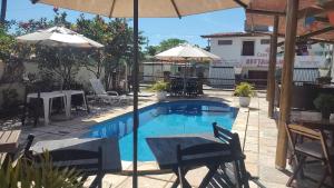 a pool with a table and chairs and an umbrella at Pousada Rosa dos Ventos in Genipabu +31 photos