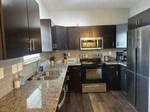 a kitchen with black cabinets and stainless steel appliances at Basic 4 bedrooms with 6 beds 15 min from downtown sleeps 9 Adults comfortably for Work crews and Large groups in Atlanta