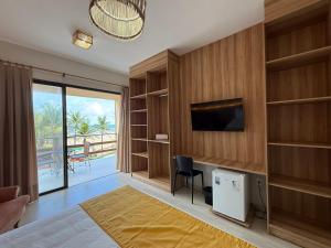 a room with a desk with a television and a balcony at G2 Beach Hotel in Aquiraz