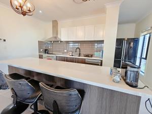 a kitchen with a counter and chairs in it at Modern Retreat by Underwood market&51 Area in Kuraby