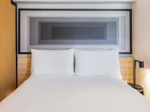 a bedroom with a white bed with a tv above it at ibis Paris Grands Boulevards Opéra 9e in Paris