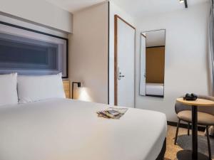 a hotel room with a white bed and a chair at ibis Paris Grands Boulevards Opéra 9e in Paris +56 photos