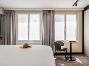 a bedroom with a white bed and a chair and windows at ibis Paris Grands Boulevards Opéra 9e in Paris