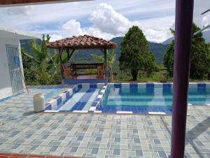 a swimming pool with a gazebo next to a house at Finca de las banderas in Jardin