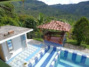 a swimming pool with a gazebo next to a house at Finca de las banderas in Jardin
