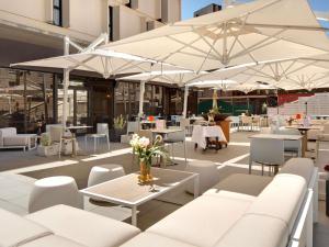 a patio with tables and chairs and white umbrellas at Mercure Montpellier Centre Comédie in Montpellier