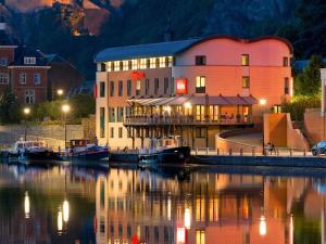 ein Gebäude mit einem Jachthafen im Wasser bei Nacht in der Unterkunft ibis Dinant Centre in Dinant