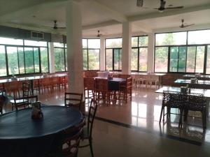 a dining room with tables and chairs and windows at Natraj hotel rooms and restaurant in Motīnāla