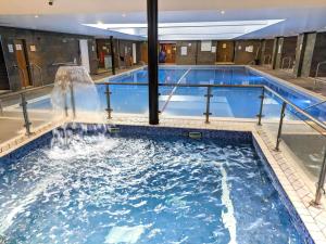a large swimming pool with a waterfall in a building at Old Thorns Golf Resort And Spa Hampshire by Accor in Liphook +203 photos