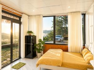a bedroom with a bed and a large window at THỎ NON GARDEN CLOUDY OCEAN VIEW in Blao Srê