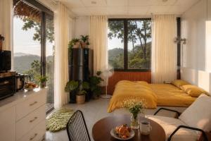 a living room with a bed and a table in a room at THỎ NON GARDEN CLOUDY OCEAN VIEW in Blao Srê