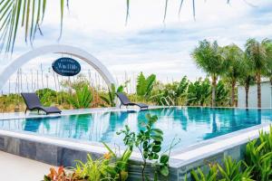 a swimming pool with two chairs in a resort at homestay windhills in Ấp Nhơn Hòa +9 photos