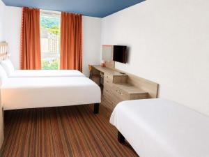 a hotel room with two beds and a television at Greet Lourdes Centre Pyrenees in Lourdes