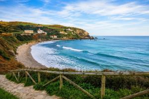 a beach with a wooden fence next to the ocean at Casa Adrianykenia in San Martín de Laspra