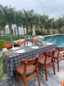 a table and chairs with a table and a pool at homestay windhills in Ấp Nhơn Hòa
