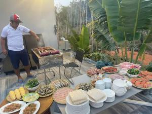 a man standing in front of a table of food at homestay windhills in Ấp Nhơn Hòa
