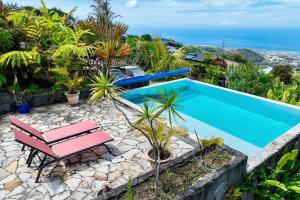 a swimming pool with a bench and the ocean at Villa TheOceane in Les Avirons
