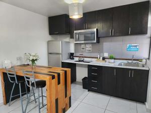 a kitchen with black cabinets and a wooden counter top at Modern Apartment in Rosarito