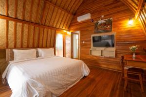 a bedroom with a bed and a tv and a desk at Villa Darma Ubud by Bali Cabin in Ubud