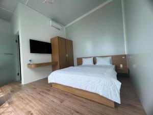 a bedroom with a large bed and a television at homestay windhills in Ấp Nhơn Hòa