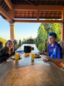 a boy and a girl sitting at a table with orange juice at The Mungseng Villa Bali in Singaraja