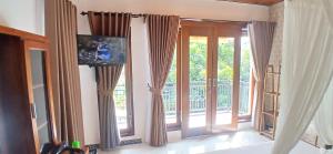 a living room with a tv and a sliding glass door at Adyara Homestay in Sidemen