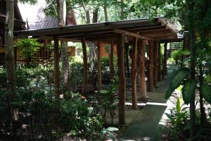 a wooden pergola with a table and chairs in a garden at Akchanok Homestay - Nature Retreat in Phitsanulok