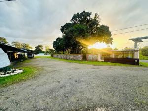 a dirt road with a fence and a tree at Cabinas del Río in Upala